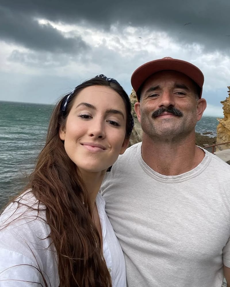 Chris Petkas and his wife Cody Sanchez on a clifftop above the ocean under storm clouds